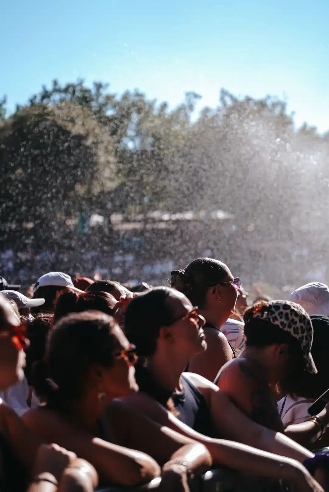 Public d'un festival, dos à l'objectif, rafraîchi par un jet d'eau